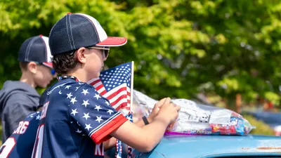 A boy in a stars-and-stripes jersey rides on the back of a float during the Fourth of July parade in Home, Washington.